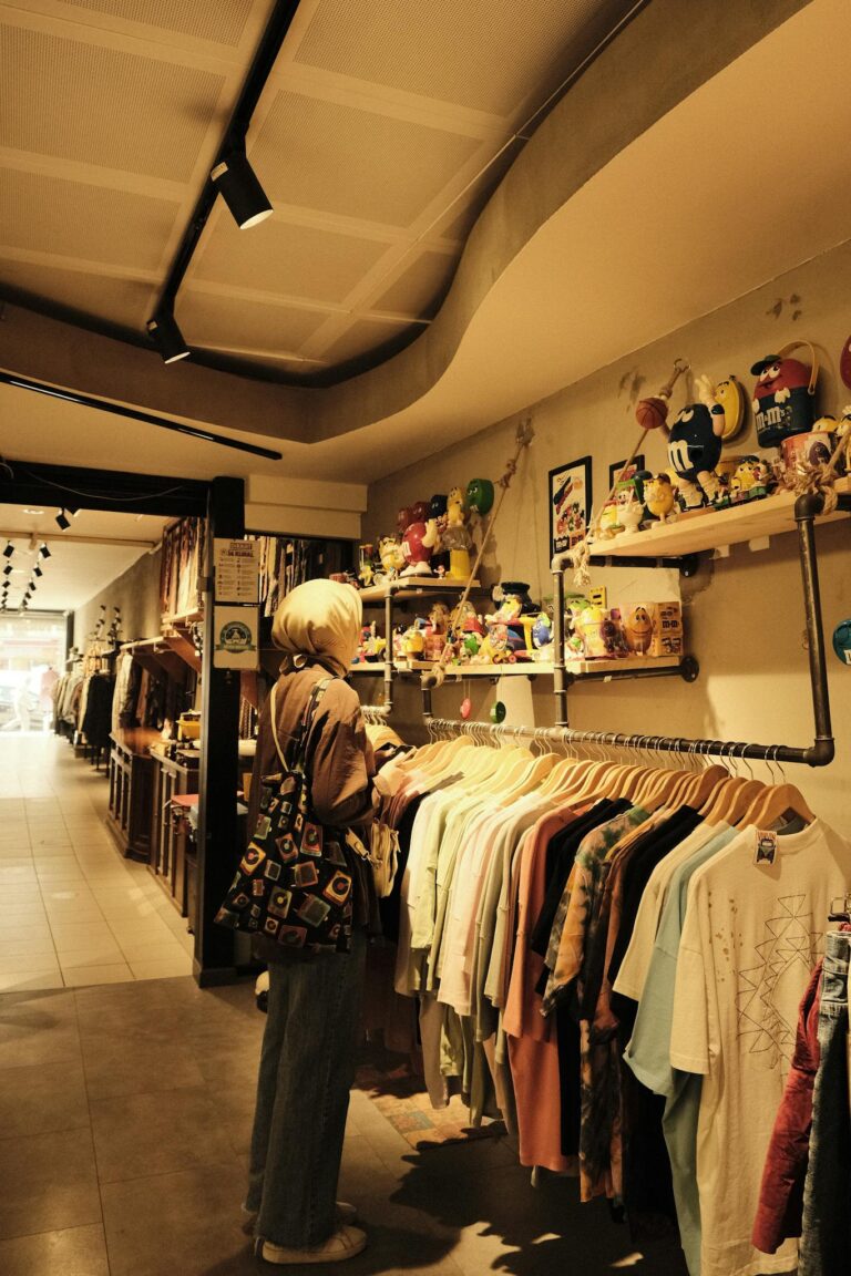 A woman examines clothes in a boutique filled with vintage items and eclectic decor.