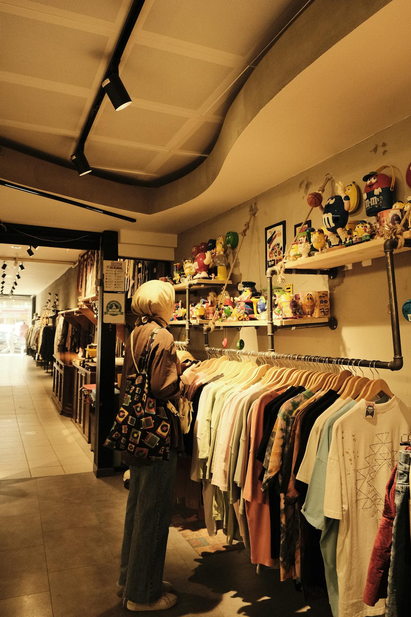A woman examines clothes in a boutique filled with vintage items and eclectic decor.
